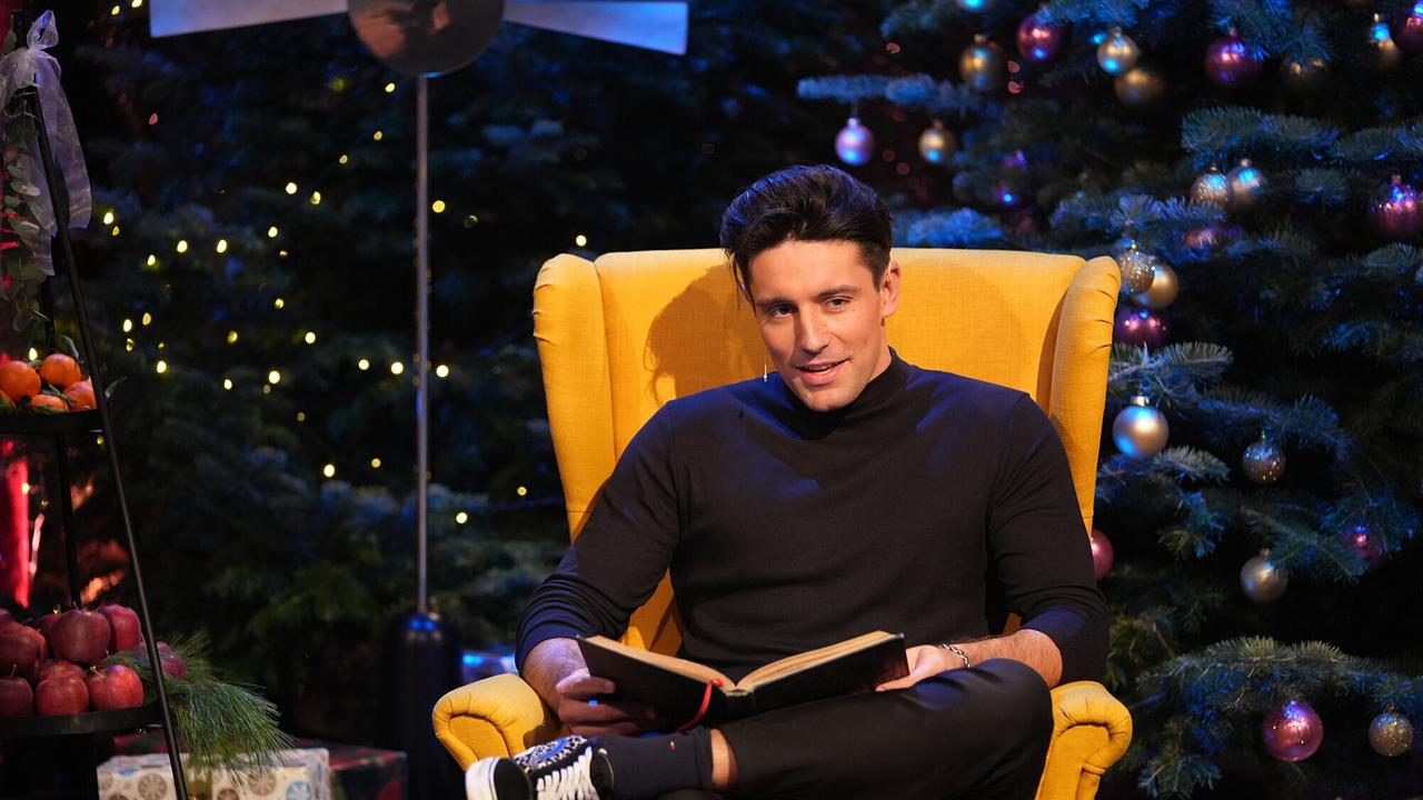 Alexander Eder liest auf einem gelben Stuhl eine Weihnachtsgeschichte vor. 