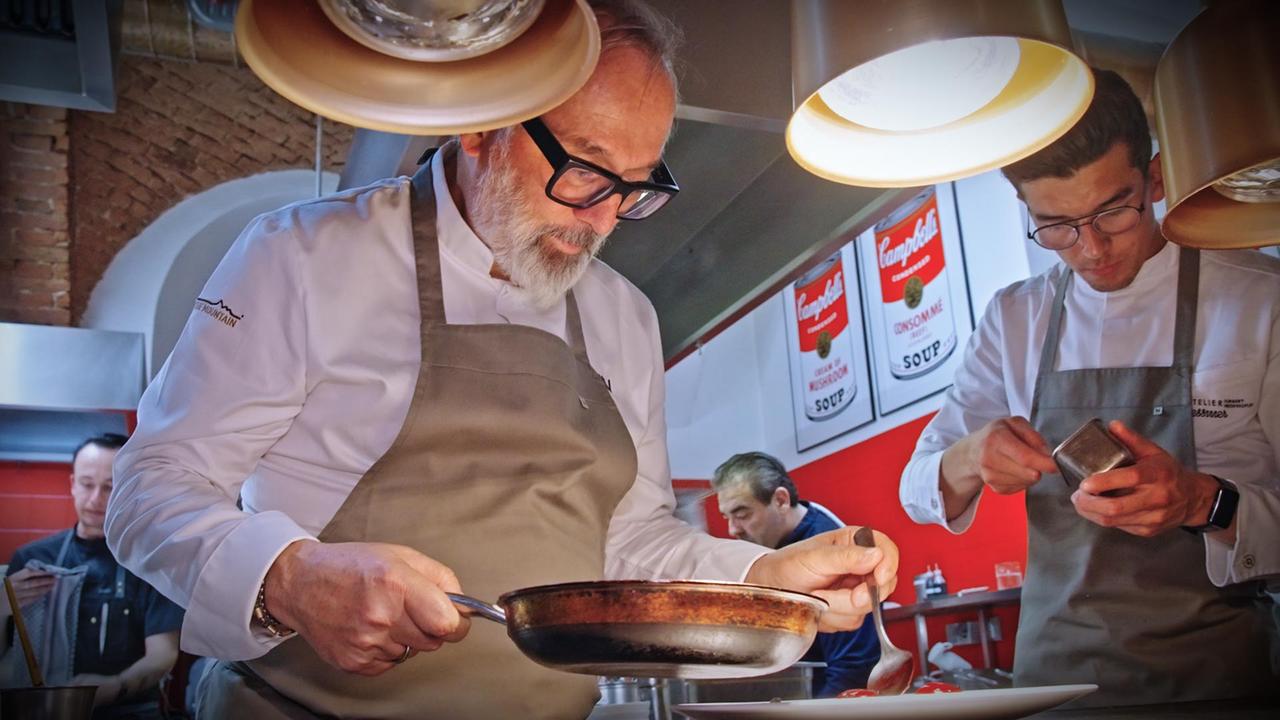 Norbert Niederkofler und ein weiterer Koch beim Anrichten eines Tellers in der Küche.