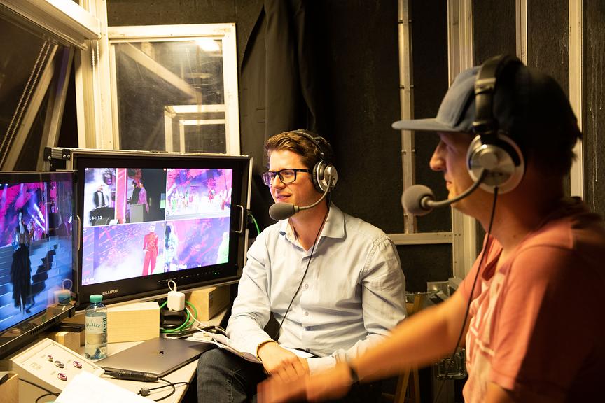 Ein Blick hinter die Kulissen der Audiodeskription. Zwei Männer sitzen mit Headset und Mikrophon vor den Bildschirmen und geben einen Einblick in ihre Arbeit.