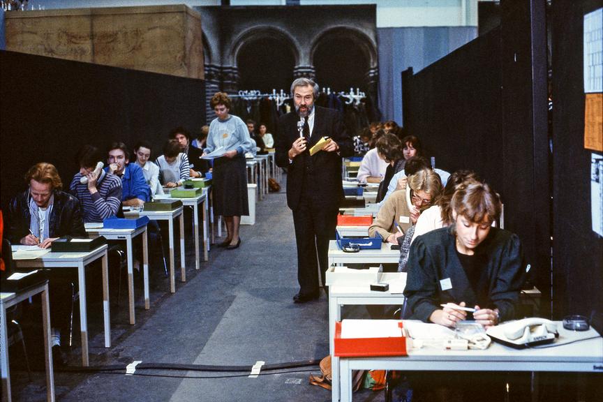 1985 – Ernst Wofram Marboe steht in der Vorbauhalle zwischen den Tischen mit denTelefonistinnen und erklärt, wie die Anrufabwicklung in der Spendenzentrale funktioniert. 